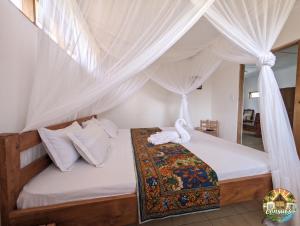 a bedroom with a canopy bed with white curtains at Consul's House Vilanculos in Vilanculos