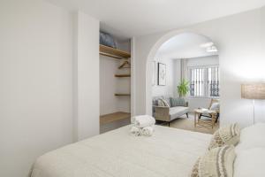 a white bedroom with a bed and a living room at Vicente Espinel Apartment in Ronda