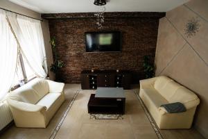 a living room with two couches and a tv on a brick wall at Sapphire Chalet - Moieciu de sus in Moieciu de Sus