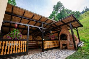 a wooden pavilion with a fireplace in a yard at Sapphire Chalet - Moieciu de sus in Moieciu de Sus