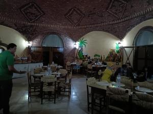 a group of people sitting at tables in a restaurant at Qasr El Bagawat Hotel in ‘Ezbet Halfa