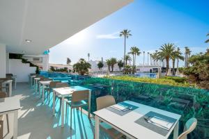a restaurant with tables and chairs and a pool at THB Sa Coma Platja in Sa Coma