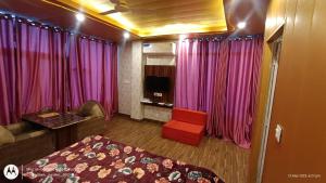 a bedroom with pink curtains and a bed and a couch at Hotel Pine View Villa in Dagshai