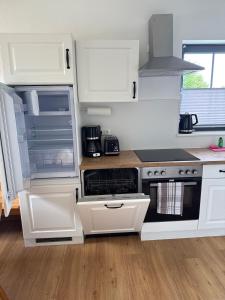 a kitchen with white cabinets and a stove top oven at Ruhig wohnen in Hüttblek in Hüttblek +6 photos