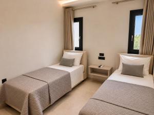 two beds in a room with two windows at Amara 2 bedrooms apartment - Alykanas in Alikanas