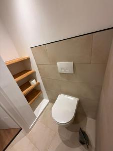 a bathroom with a white toilet and some shelves at EJ Apartments in Gartow +8 photos