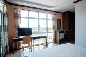a bedroom with a desk with a computer and a large window at Breezehill Khao Kho Hotel in Khao Kho