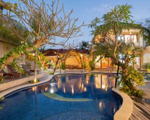 a swimming pool in front of a house with trees at MJ Villa Sanur in Sanur