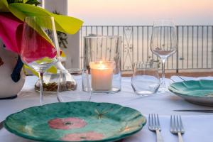 a table with a plate and glasses and a candle at La Terrazza del Sole a Positano in Positano +35 photos