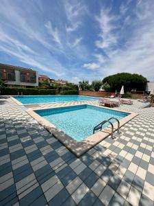 a large swimming pool with a tile floor and a blue at Solleone 18 - Sea, Sun e Pool in Cavallino-Treporti