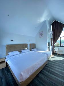 a large white bed in a room with a large window at D'Mount Sky Homestay Syariah in Bukittinggi +10 photos