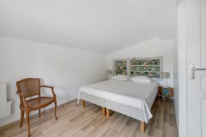 a white bedroom with a bed and a chair at Gite Du Cerisier - Varennes in Varennes +13 photos