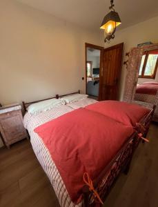 ein Schlafzimmer mit einem großen Bett und einer roten Decke in der Unterkunft Chalet Anna Chiara in Arola