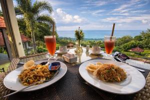 ein Tisch mit zwei Tellern mit Speisen und Getränken in der Unterkunft The Hamsa Bali Resort in Lovina