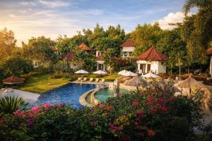 ein Resort mit einem Pool mit Sonnenschirmen und Blumen in der Unterkunft The Hamsa Bali Resort in Lovina