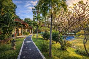 ein Weg durch einen Garten mit Palmen und einem Haus in der Unterkunft The Hamsa Bali Resort in Lovina