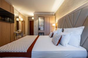 a bedroom with a large bed with white sheets and pillows at Hissar Spa Hotel in Hisarya