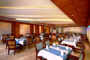 uma sala de jantar com mesas e cadeiras brancas em Diana Heights Luxury Hotel em Nedumbassery