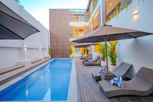 a pool with chairs and umbrellas next to a building at Anandani Suites in Canggu