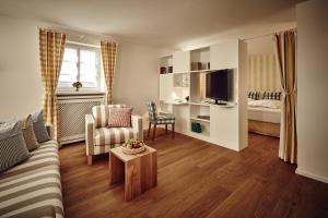 a living room with a couch and a chair and a television at Hotel Schloss Freudental in Allensbach +18 photos