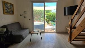 a living room with a couch and a table and a sliding glass door at Laure Cabasson in Bormes-les-Mimosas