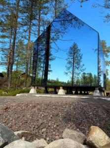 a bridge in the middle of a park with trees at Sāmeland Retreat, Mirrored Glass Cabins, Swedish Lapland in Arvidsjaur