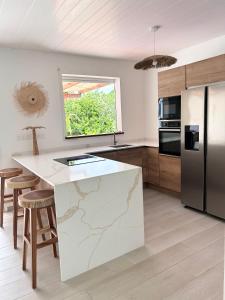 a kitchen with a white counter and a refrigerator at Villa neuve Casa Helena - Piscine privée et jardin - 6 pers - Saint-Esprit - Sud Martinique in Quartier Palmène