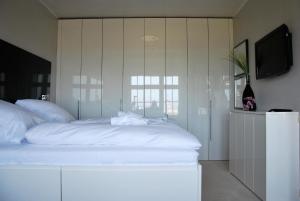 a bedroom with a large white bed and a television at Am Seedeich 7 SE10 Seesicht in Cuxhaven