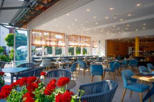 a restaurant with blue chairs and tables and flowers at Hotel Meschenmoser in Langenargen