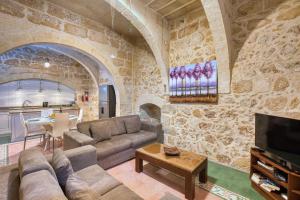 a living room with a couch and a tv at Kikka Holiday Home in Xagħra