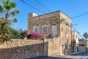 an old stone building with a stone wall at Kikka Holiday Home in Xagħra