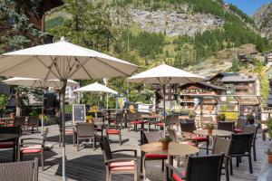 an outdoor patio with tables and chairs and umbrellas at Hotel Bristol in Zermatt
