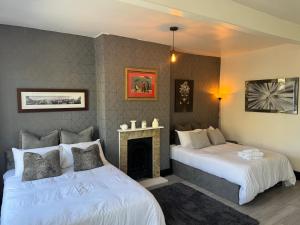 two beds in a room with a fireplace at The Cloud in Alderley Edge