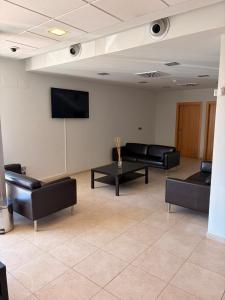 a waiting room with black leather furniture and a flat screen tv at Hotel del Vino in Cariñena