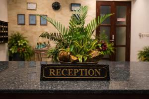 Ein Schild mit der Aufschrift „Rezeption“ steht auf einem Tresen mit einer Pflanze. in der Unterkunft The Hamsa Bali Resort in Lovina + 61 Fotos
