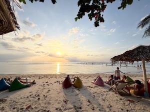a group of people sitting on the beach at sunset at Umbrella tree เต้ทน์ in Nathon Bay