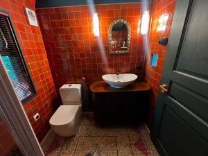 Ein rot gefliestes Badezimmer mit Toilette und Waschbecken in der Unterkunft 0'Bama - Unique Upcycled Tiny House in Selgas + 5 Fotos