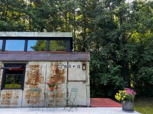 ein altes Gebäude mit einem Schild und Stühlen in der Unterkunft 0'Bama - Unique Upcycled Tiny House in Selgas