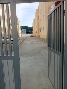 an open gate to an empty street with buildings at Maryline house in Bizerte +6 photos
