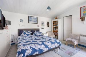 a bedroom with a blue and white bed and a chair at Chambre d'hôte Lajarrieleduc in La Jarrie