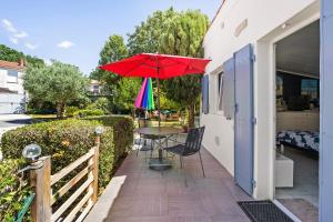 a patio with a table and a colorful umbrella at Chambre d'hôte Lajarrieleduc in La Jarrie