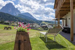 a chair and flowers on a porch with a mountain at Tieja Panoramic Lodge in Selva di Val Gardena