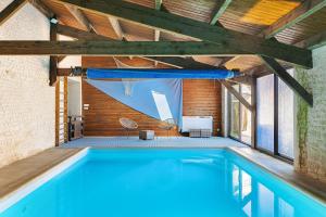 a swimming pool in a building with a wooden ceiling at Domaine Roses Des Sables in La Jarrie