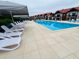 a row of chairs and umbrellas next to a pool at Łebska ostoja in Żarnowska