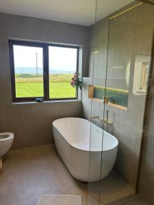 a white bath tub in a bathroom with a window at Murreigh Beag Waterville in Waterville