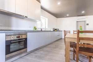 a kitchen with white cabinets and a wooden table at Flôr do Távora in Vila da Ponte