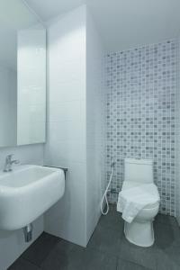 a white bathroom with a toilet and a sink at Thongchen Residence in Samut Sakhon