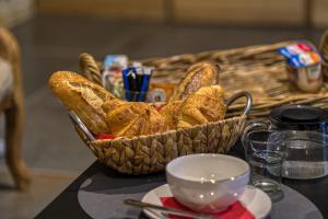 a basket of bread sitting on a table with a cup at SUITE TESORO climatisée avec piscine spa hammam et jardin avec piscine in Saint-Martial-sur-Né