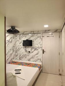 a bedroom with a bed and a tv on a marble wall at Venus Guest House in Mumbai