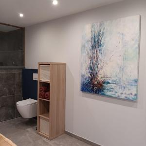 a bathroom with a toilet and a painting on the wall at Gîte Entre Semois et Forêt in Chiny +14 photos